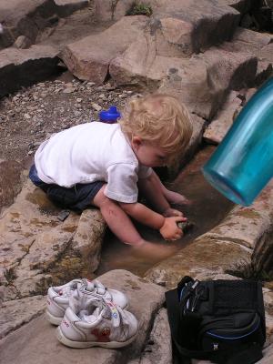 Noah pulls rocks out of the puddle.