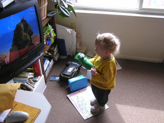 Noah stands on his Veggie Tales puzzle, holds his Veggie Tale doll
and watches Veggie Tales.
