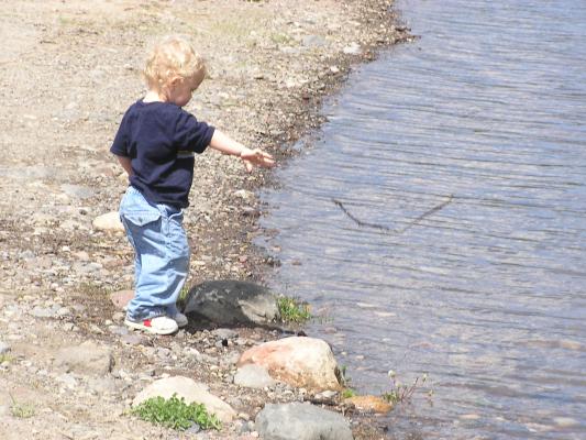 Noah throws his stick into the water.