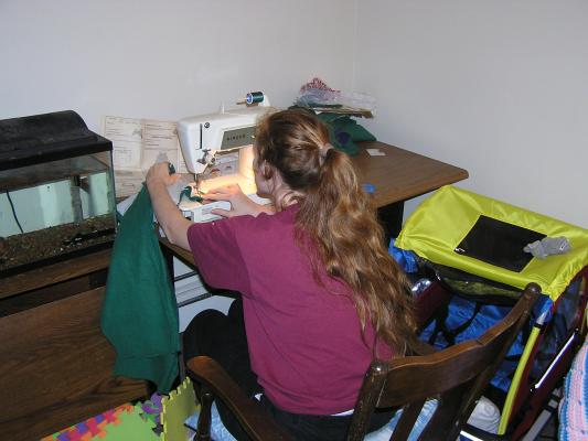 Katie is busy sewing baby clothes for the new baby.