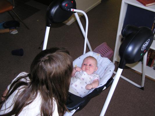 Andrea looks at Sarah in her swing.