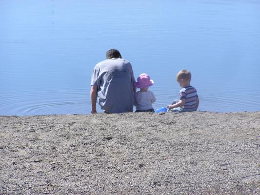 David, Sarah and Noah throw rocks in the water.