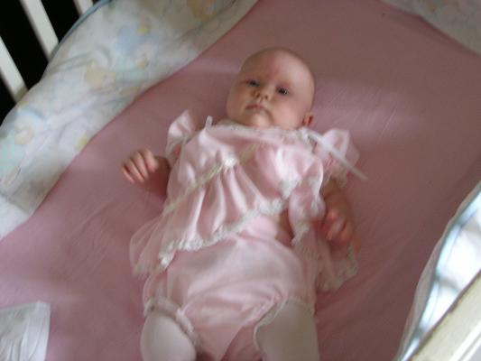 Sarah in her pink dress in her crib.