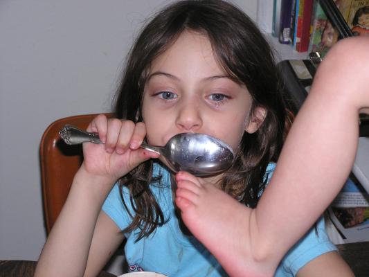 Andrea eating wiht a big spoon/ Noah's foot.