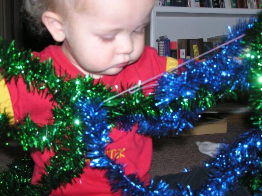 Noah plays with green and blue tinsel.