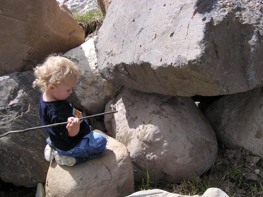 Noah climbs on some really big rocks.