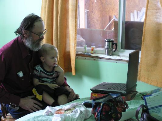 Noah watches Grandpa play on the computer.