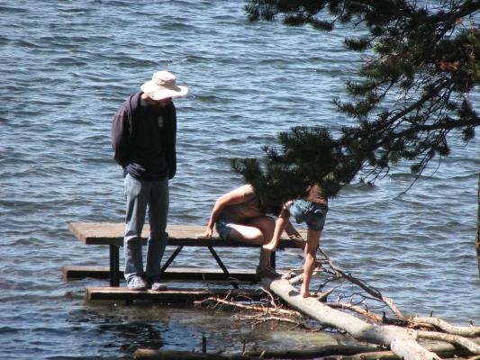 David and kids on picnic table in water.