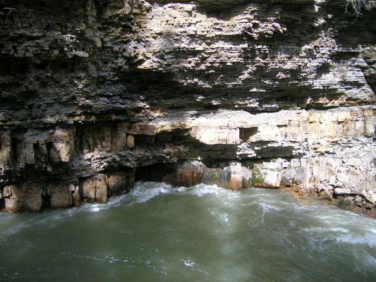Sedimentary layers above the eroding surface of the river.