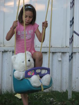 Andrea plays with bear in a swing. 