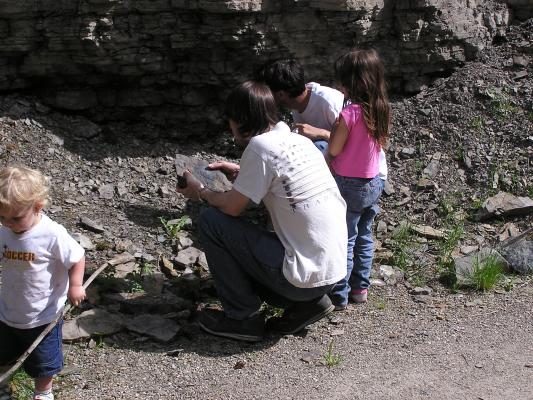 Noah with his stick and David, Andrea and Myke look at rocks.