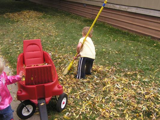 Sarah and Noah play with leaves in the wagon.