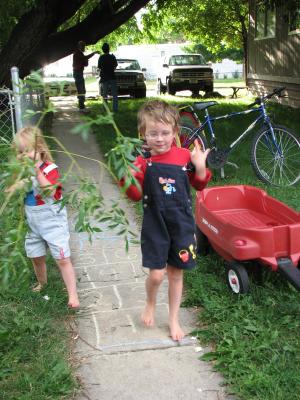 Sarah in overalls with tree branch. and Noah