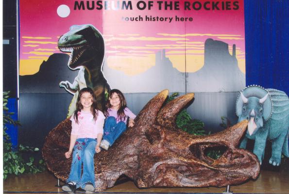 Malia and Andrea sit on a dinosaur from the Museum of the Rockies.