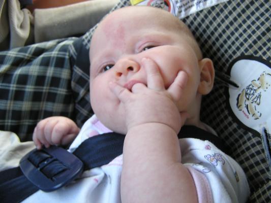 Sarah sucks her ring finger in her carseat.
