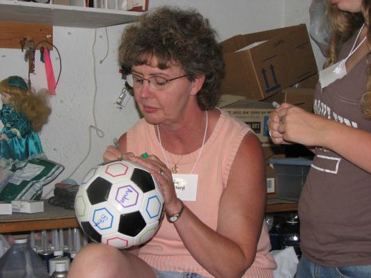 Cheryl signs the soccerball.