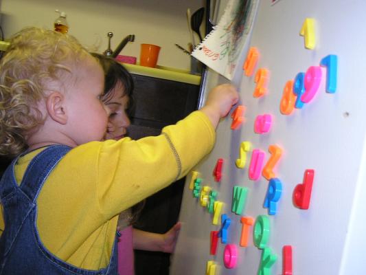 Noah plays with the letters on the fridge.