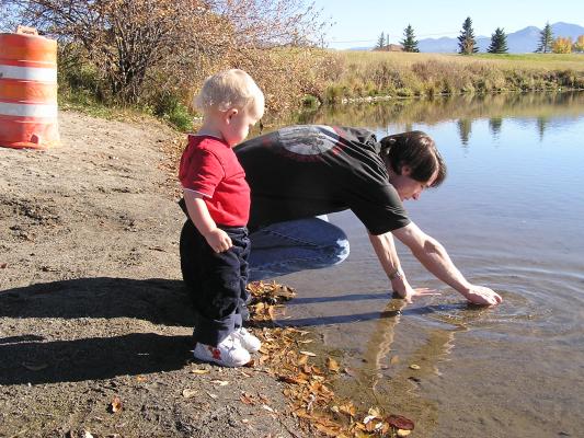 David reaches into the water to get some good rocks for Noah to throw.
