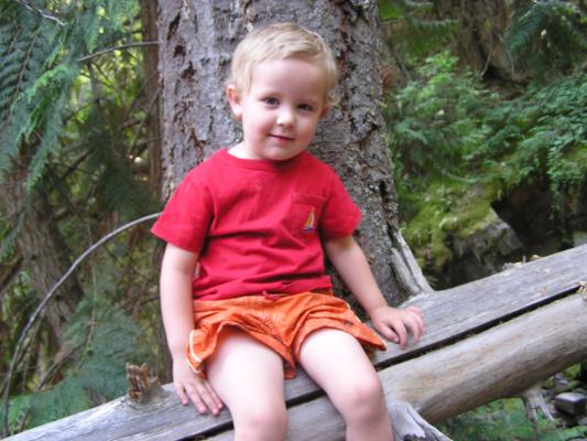 Noah rests  on a log during a hike