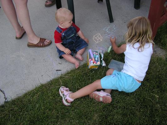Noah watches Mickala draw with chalk at the 4th of July barbeque.