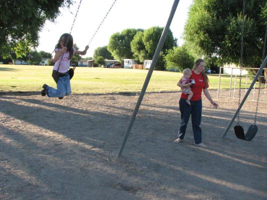 Andrea swinging. Sarah and Katie walking by.