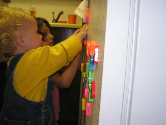 Noah plays with the letters on the fridge.