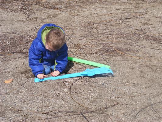 Noah puts dirt on a rake at the playground