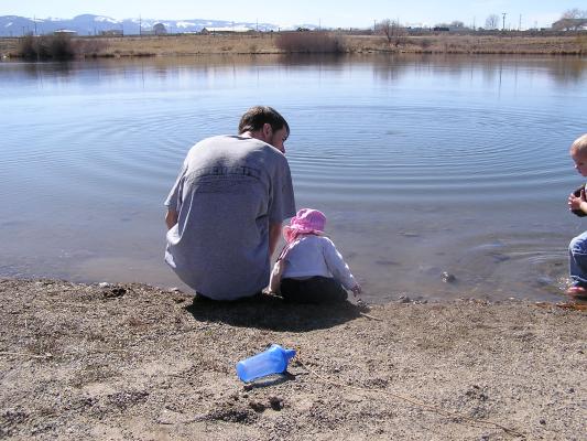 David, Sarah and Noah throw rocks in the water.