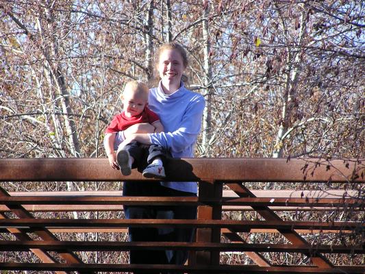 Noah and Katie on a bridge in the woods.