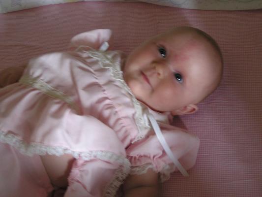 Sarah in her pink dress in her crib.