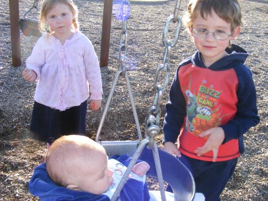 Joshua's first time in a park swing. Sarah and Noah help push