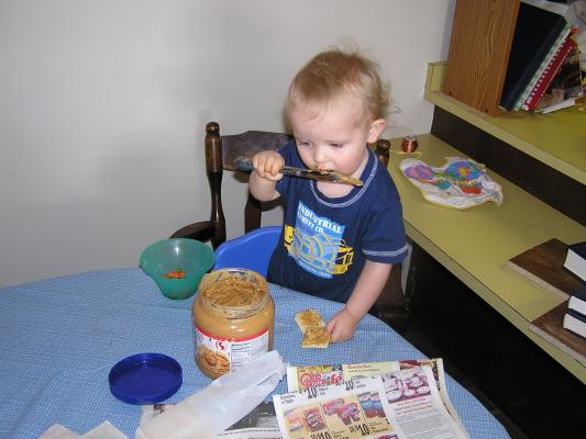 Noah puts peanut butter on crackers.
