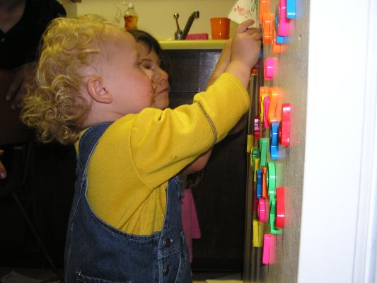 Noah plays with the letters on the fridge.