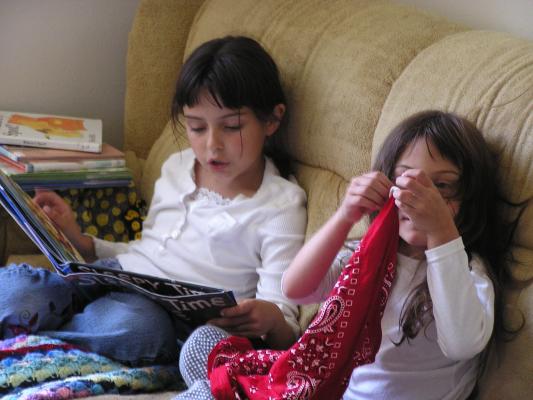 Malia reads a story to Andrea on the couch.