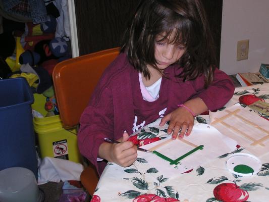 Andrea paints popsickle stick picture frames.