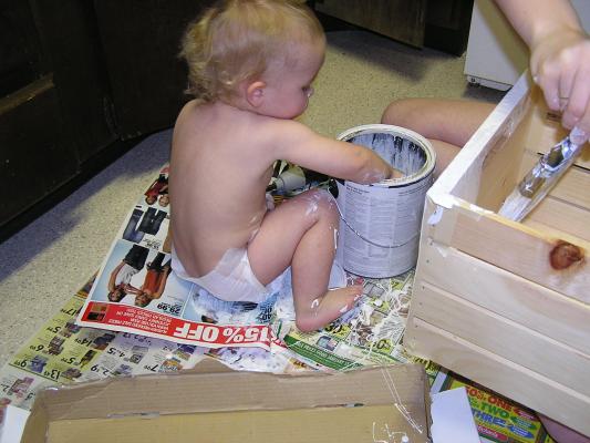 Noah is helping mommy paint the box.