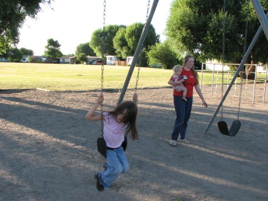 Andrea swinging. Sarah and Katie walking by.