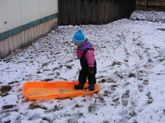 Sarah plays with sled in first snow.