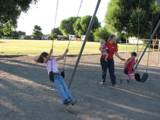 Andrea swings. Katie and Sarah give Malia a push.