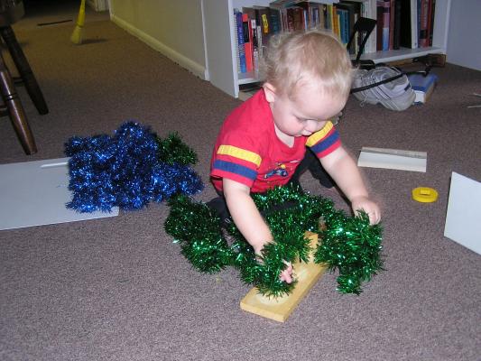 Noah plays with green and blue tinsel.