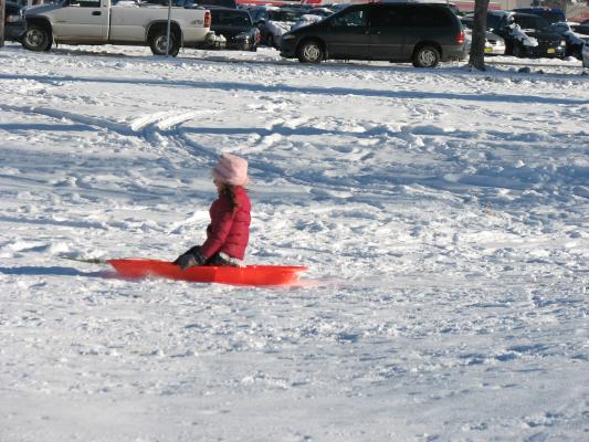 Andrea sledding by Town and Country grocery store.
