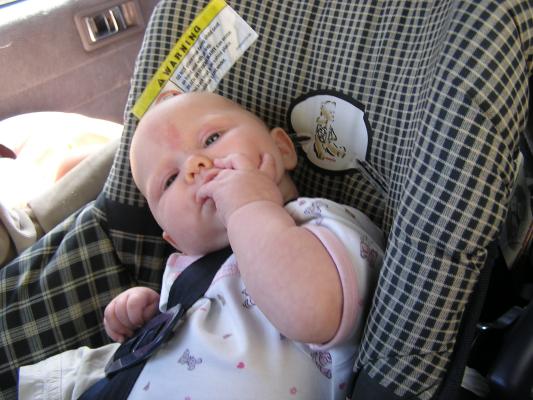 Sarah sucks her ring finger in her carseat.