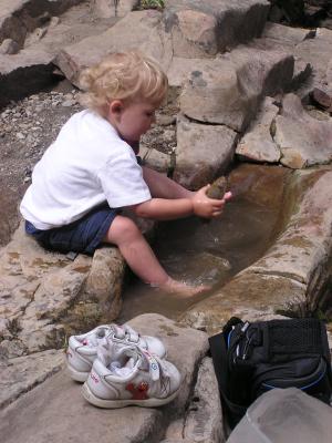 Noah pulls another rock out of the puddle.