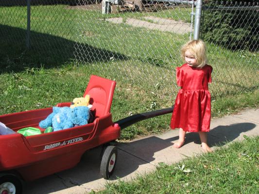 Sarah pulls her dolls in the wagon.