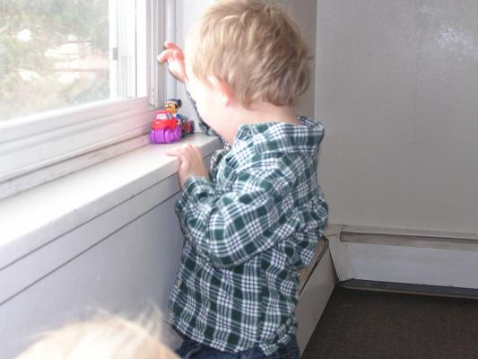Noah plays cars on the window.