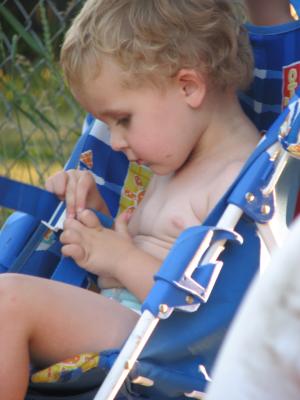 Noah tries to fasten the buckel on the stroller