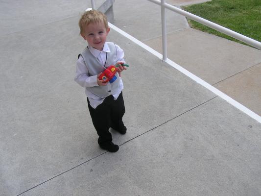 Noah plays with a camera. He is all dressed up
