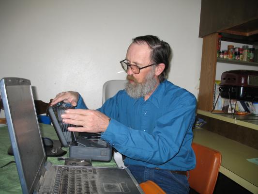 Robert digs through David's CDs looking for Fedora 6 (Linux).