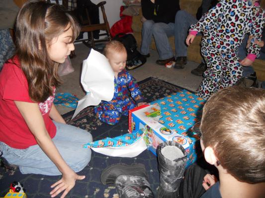 Andrea nad Sarah watch Josh open a first birthday gift. 