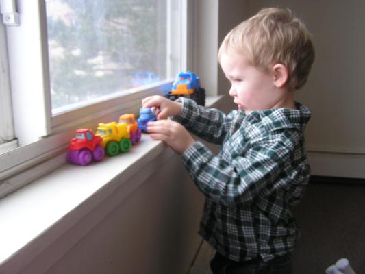Noah plays cars on the window.